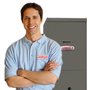 A technician standing with arms folded in front of a furnace