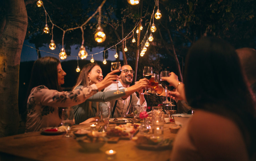 Friends toasting with wine and beer at rustic dinner party