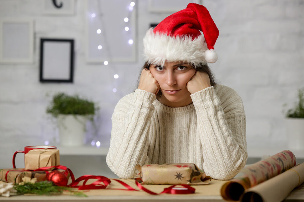 A scowling woman wearing a Santa cap