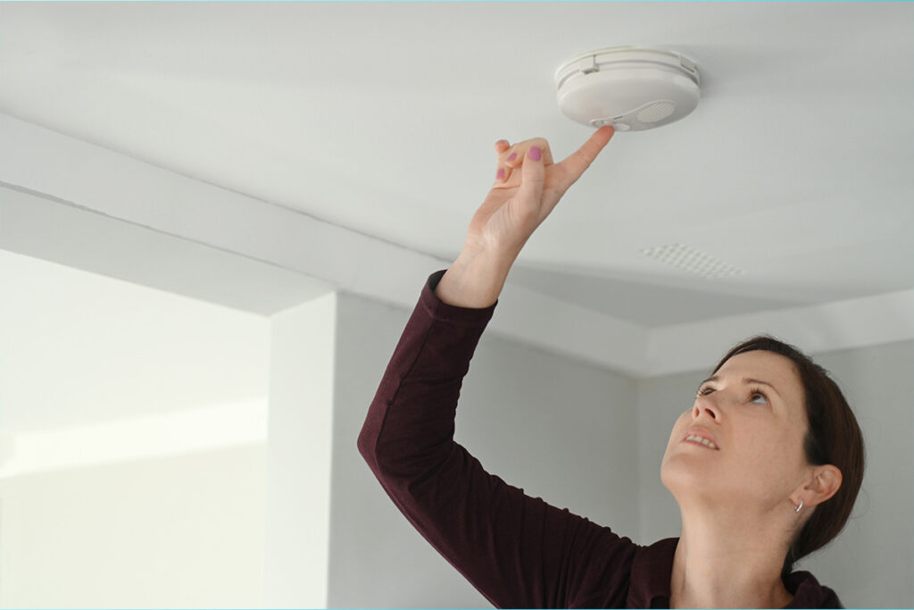 A woman checking her smoke alarm